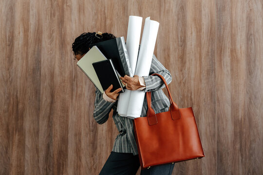 Overworked Businesswoman Carrying Documents and Blueprints