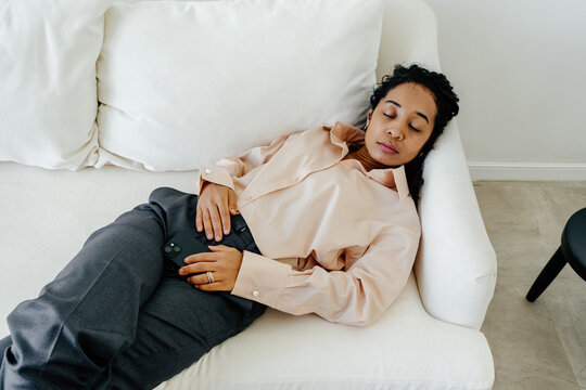 Exhausted Businesswoman Resting on Sofa with Smartphone After Work
