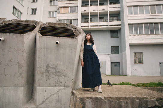 Young woman stands near large concrete structure in urban location