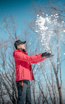 Man Throwing Snow into the Air on a Sunny Winter Day