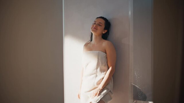 Woman towel leaning wall enjoying sunlight. Closeup portrait after spa shower.