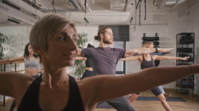 Group of people practicing hatha yoga. Man and women doing meditation pose at yoga studio. Mindfull people doing ashtanga pose at yoga session. People relaxing and catching spiritual zen.
