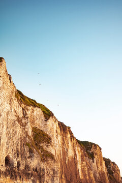 Cliffs Meet Blue Sky With Birds Flying Over the Coastline at Sunset