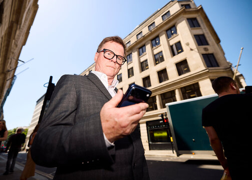Senior entrepreneur checks his phone outdoors