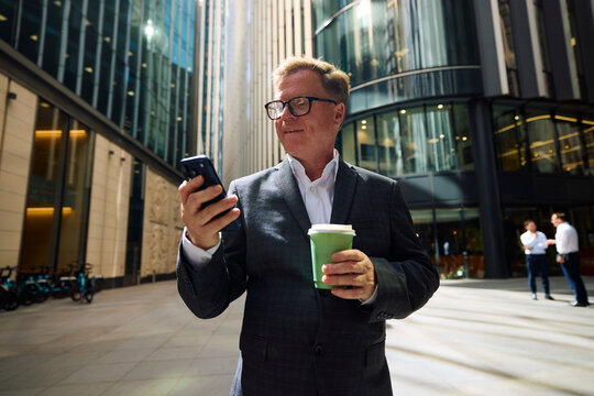 Senior businessman checks his phone outdoors