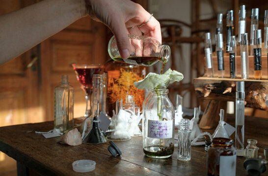Hands of a perfumer blending fragrance ingredients in a studio