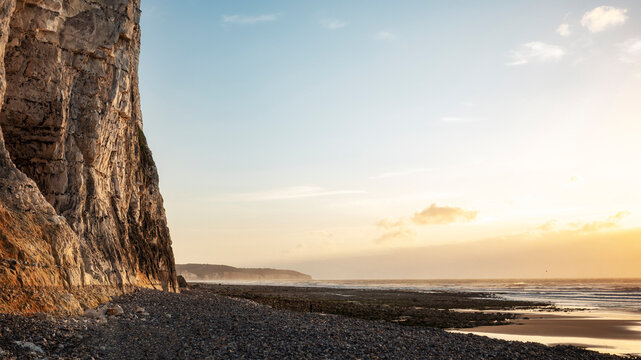 Cliffs and Beach at Sunset With Calm Water and Clear Sky