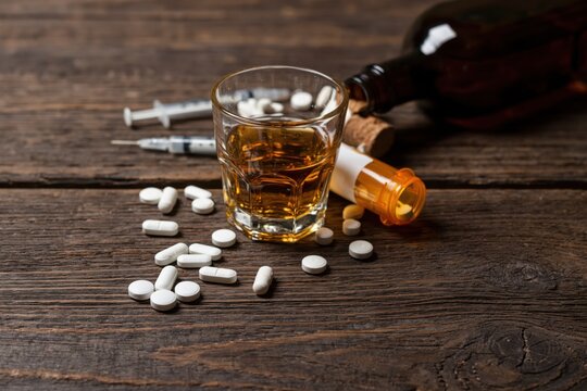 The Glass of Whiskey and Pills on a Rustic Wooden Table