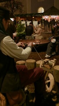 Artisan Spinning Wool with Traditional Wooden Tool at Christmas Fair &ndash; Vertical