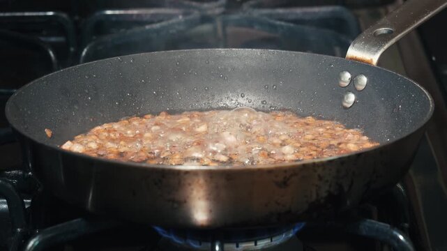 Diced pancetta frying and bubbling in a frying pan