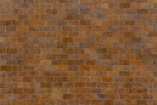 Aged sandstone brick wall with handmade bricks. Multi-colored brown and ochre masonry surface for a vintage background.