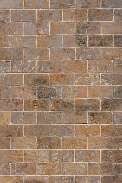 Weathered clay block facade with vertical masonry lines. Shabby terracotta surface with lime stains and scratched details for a grunge background.