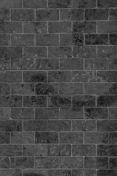 Weathered anthracite stone wall with vertical block layouts and visible lime traces. Distressed charcoal masonry facade with scratches and mineral stains for a dark industrial background.