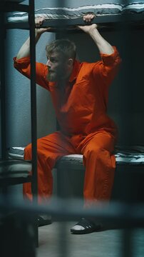 Young male prisoner sitting on a bed in a shared prison cell, serving sentence