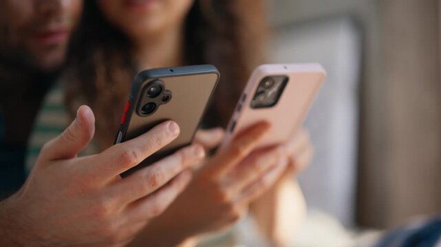 Closeup couple hands holding phones together home browsing smartphones weekend