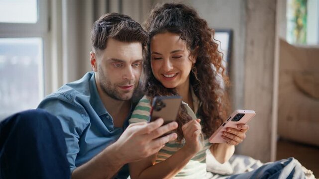 Couple browsing smartphones cozy home. Man woman comparing phones happy weekend.