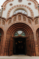 Fototapeta premium Ornate brick entrance portal with carved decorative details at the historic synagogue. Fine craftsmanship highlighting the Art Nouveau architecture of Subotica, Serbia.