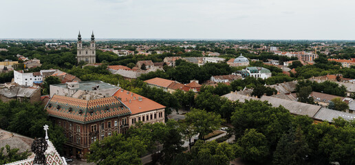 Fototapeta premium Elevated panoramic view over the historic center of Subotica, Serbia, with colorful rooftops and church towers. A broad urban landscape showcasing the city's distinctive architecture.