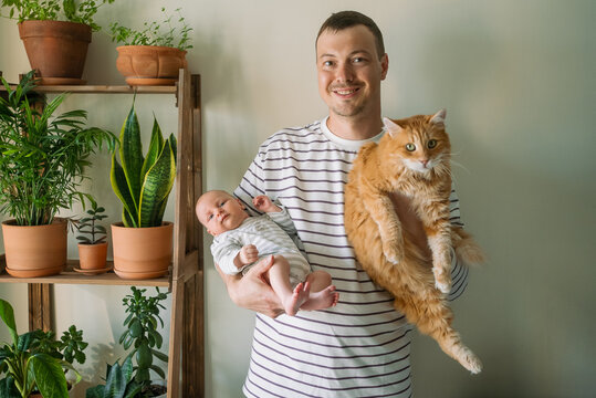 Father holding his newborn baby and an orange ginger cat, symbolizing the joy and responsibilities of new parenthood, family bonding, and a loving home environment