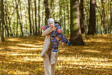 Fototapeta premium Smiling Baby in Mother's Arms During Autumn Forest Walk