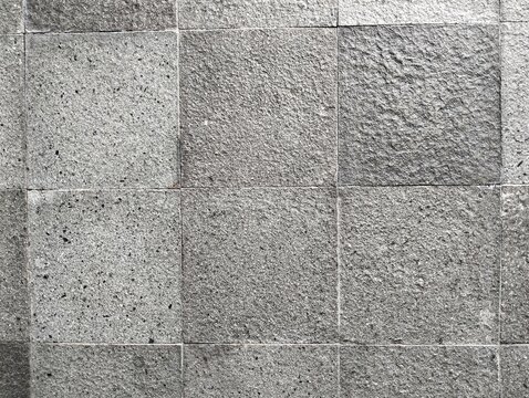 Grey natural andesite stone wall tiles texture background. Abstract square volcanic stone pattern backdrop for architectural, interior, or exterior design