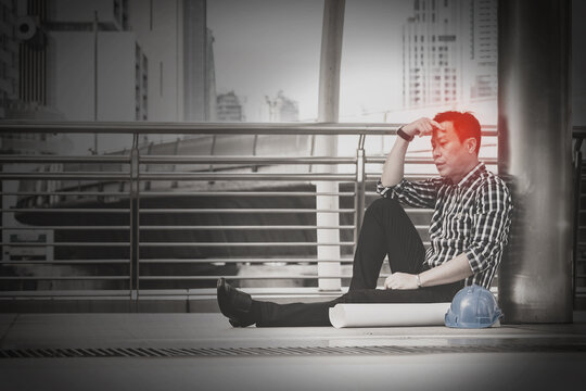 Asian engineer man who sitting on the floor in feeling sad because his business failed and unemployed. Business failed concept.