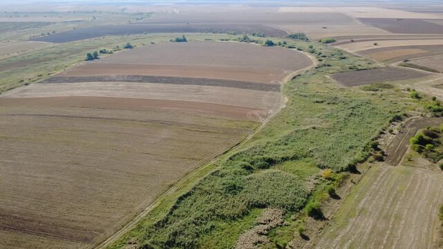 Panoramic Drone Shot Over Summer Farmland. Stunning Drone Aerial of Cultivated Fields and Green Vegetation.