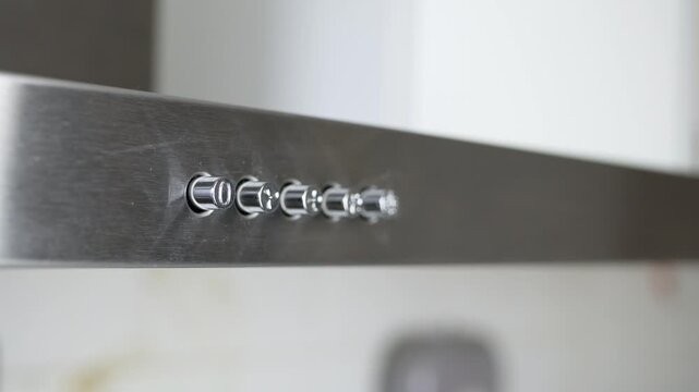Finger Pressing Kitchen Range Hood Power Button Closeup. Man Pressing Stainless Steel Range Hood Switch Detail.