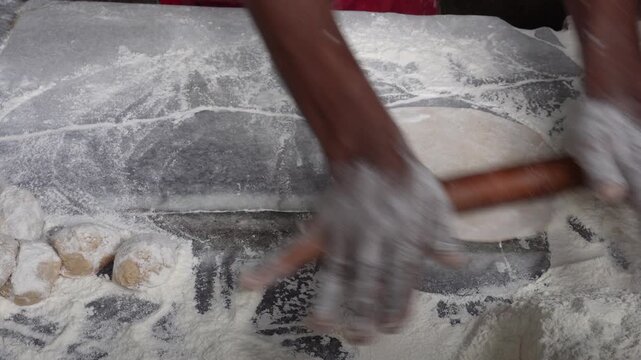 Hands shaping roti dough with traditional skill
