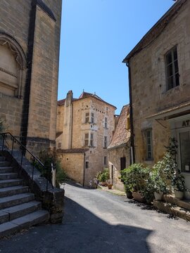 Scenic historic street view next to the abbey church featuring a prominent Renaissance mullioned window facade in Saint-Cyprien, Dordogne, France