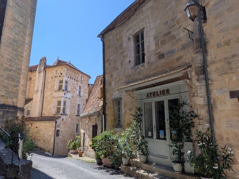 Charming street view in the medieval village of Saint-Cyprien showing an artist atelier shopfront and a historic building with Renaissance mullioned windows, Dordogne, France