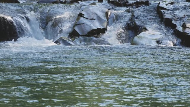 Mountain River with Small Waterfall Flowing Over Smooth River Rocks 