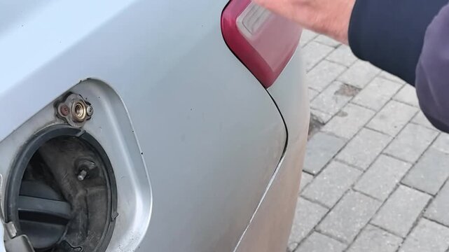 Man unscrewing LPG adapter from car fuel tank after gas refueling