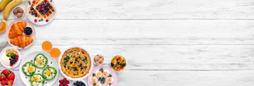 Breakfast or brunch corner border on a white wood banner background. Overhead view. Assortment of fruits and sweet and savory food items. Copy space.