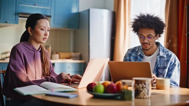 Couple working laptops kitchen table. Roommates studying morning home together.
