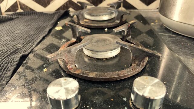 Dirty gas stove with greasy burners in a home kitchen, household cleaning, kitchen hygiene, domestic maintenance, everyday chores.