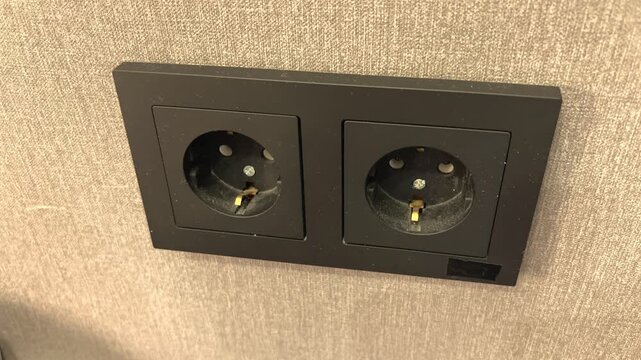 A dirty black electrical outlet mounted on a wall indoors, home maintenance, electrical safety, renovation concept, inspection, household infrastructure.