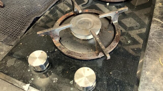 A dirty gas stove with greasy burners in a home kitchen before cleaning, household chores, sanitation, kitchen maintenance, domestic life.