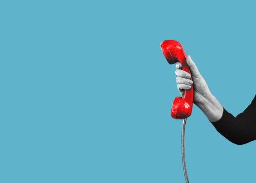 A hand holds a red landline telephone with copy space, isolated on free background. Flat design art.