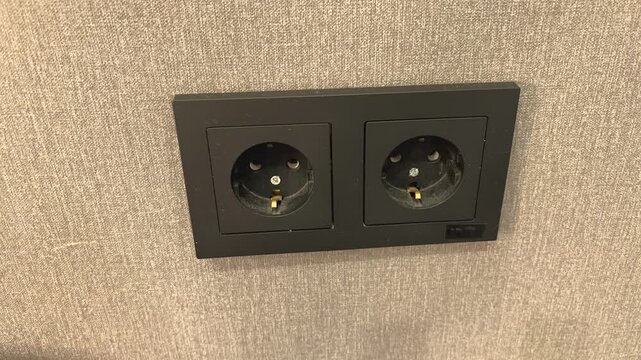 A dirty black electrical outlet mounted on a wall indoors, home maintenance, electrical safety, renovation concept, inspection, household infrastructure.