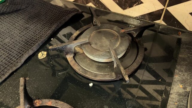A dirty gas stove with greasy burners in a home kitchen before cleaning, household chores, sanitation, kitchen maintenance, domestic life.