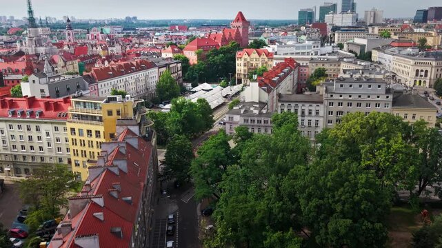 Aerial View Poznan City Street Market Square Buildings Skyline. A high angle drone perspective capturing a traditional open air market square with white tents, surrounded by historic red roof