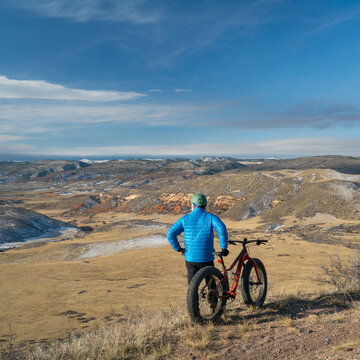senior male riding a fat bike on Cheyenne Rim in Red Mountain Open Space, late fall or winter scenery with snow