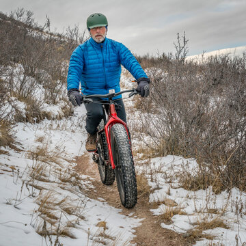 senior male riding a fat bike on Cheyenne Rim in Red Mountain Open Space, late fall or winter scenery with snow