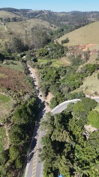 Imagem a&eacute;rea de estrada usada por ciclistas em Saba&uacute;na, Mogi das Cruzes, atravessando vegeta&ccedil;&atilde;o densa, propriedades rurais e colinas na regi&atilde;o do Alto Tiet&ecirc; paulista.
