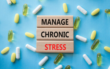 Manage Chronic Stress symbol. Concept words Manage Chronic Stress on wooden blocks. Beautiful blue background with pills. Healthcare and Manage Chronic Stress concept. Copy space.