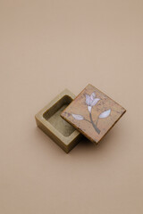 Fototapeta premium Elegant small decorative box with a light-colored floral inlay design on its lid, presented on a subtle, neutral background, perfect for a chic display