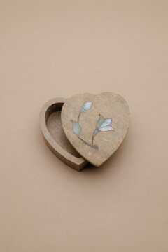 Elegant heart-shaped stone trinket box with delicate floral inlay, partially open on a soft beige background, ready for your precious keepsakes