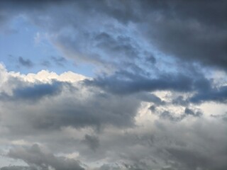 Obraz premium Blue sky with contrasting bright white cumulus and dark rain clouds
