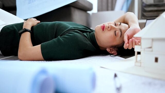 Tired architect resting on blueprints after long working hours